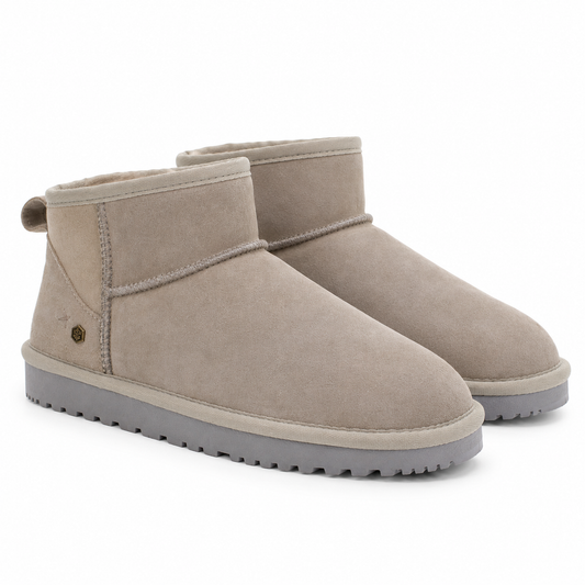 A pair of classic mid-calf suede boots in a taupe color, featuring a grey sole and a small pull tab on the heel, set against a plain white background.