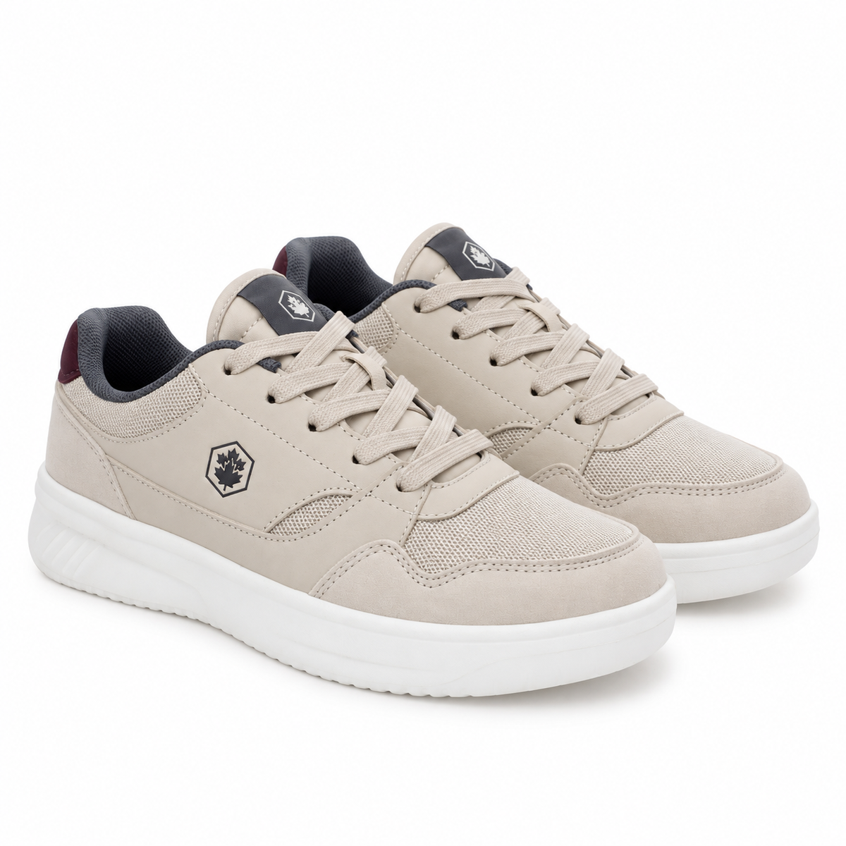 A pair of beige low-top sneakers with white soles, dark gray laces and lining, and a small black geometric logo on the side, shown against a plain white background.